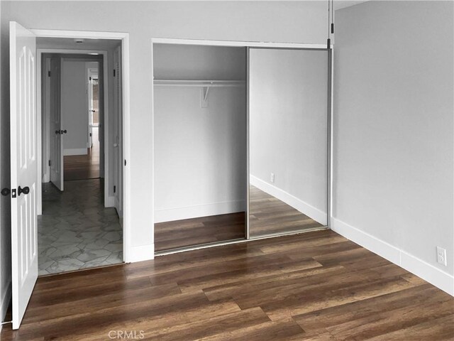 unfurnished bedroom featuring a closet and dark hardwood / wood-style floors