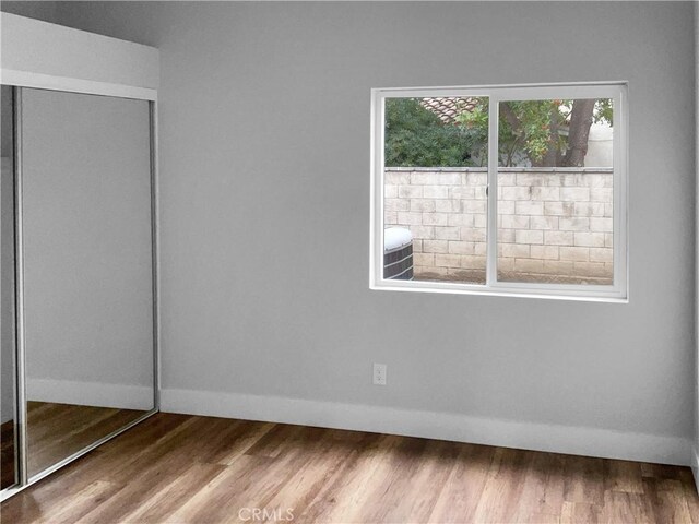 unfurnished bedroom featuring wood-type flooring and a closet