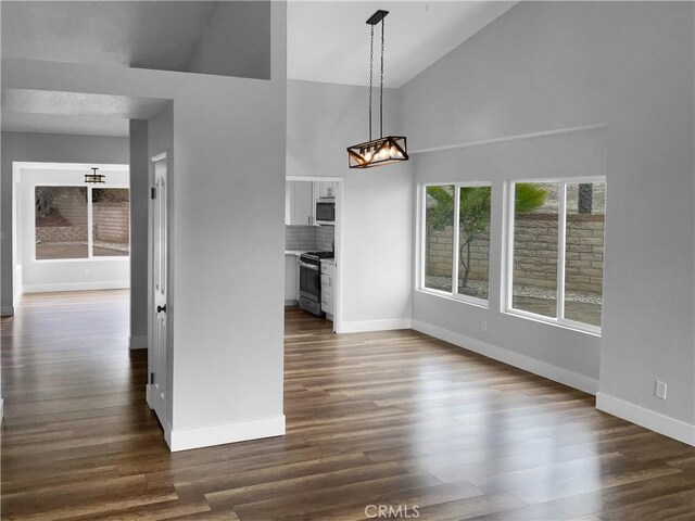 unfurnished living room featuring dark wood-type flooring and high vaulted ceiling