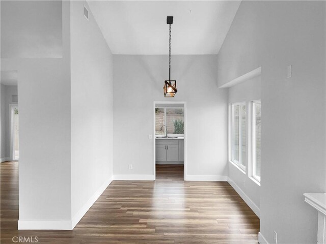 unfurnished dining area with sink, dark wood-type flooring, high vaulted ceiling, and a healthy amount of sunlight