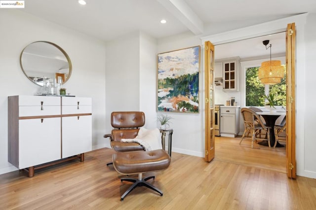 living area with light hardwood / wood-style floors and beamed ceiling