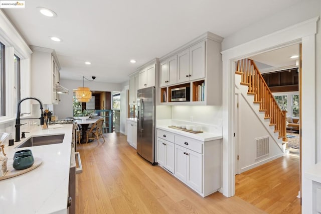 kitchen featuring white cabinetry, stainless steel appliances, sink, and hanging light fixtures