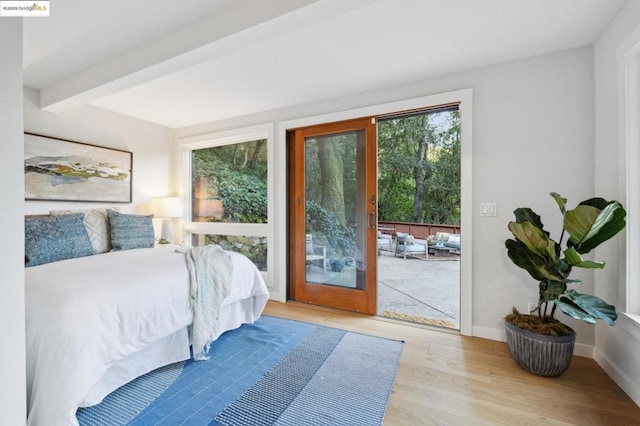 bedroom with beam ceiling, access to exterior, and light hardwood / wood-style floors