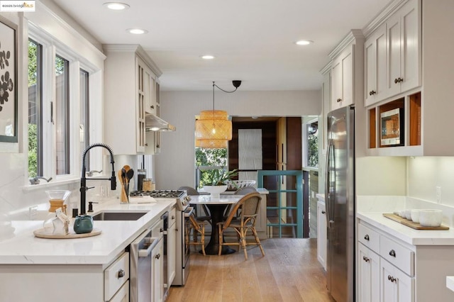 kitchen with appliances with stainless steel finishes, decorative light fixtures, sink, and a wealth of natural light