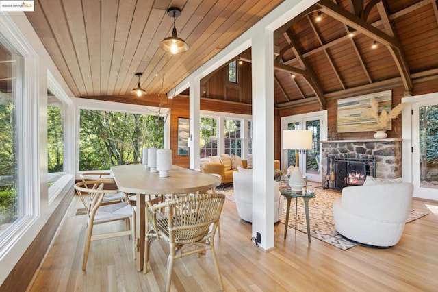 sunroom featuring vaulted ceiling with beams, a stone fireplace, and wooden ceiling