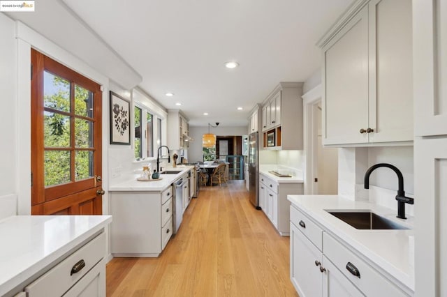 kitchen with sink, stainless steel appliances, and light hardwood / wood-style floors