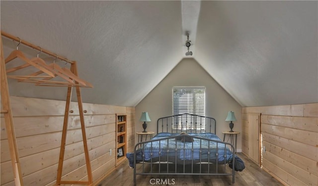 bedroom with vaulted ceiling, hardwood / wood-style floors, and wood walls