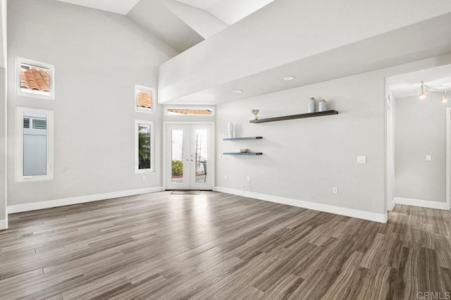 unfurnished living room with french doors, high vaulted ceiling, and hardwood / wood-style floors