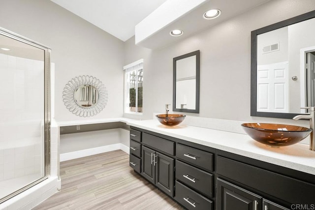 bathroom with wood-type flooring, a shower with shower door, and vanity