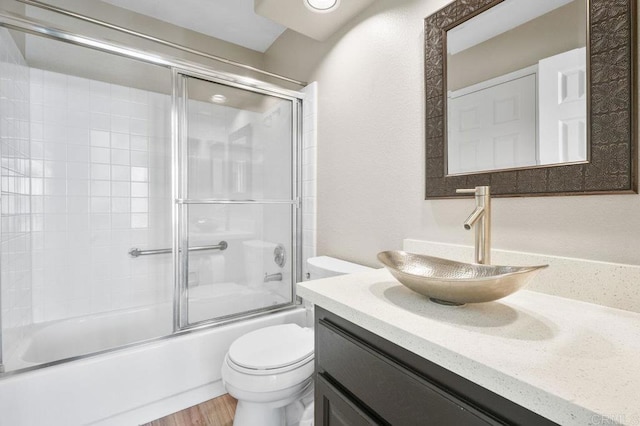 full bathroom with vanity, hardwood / wood-style floors, toilet, and combined bath / shower with glass door