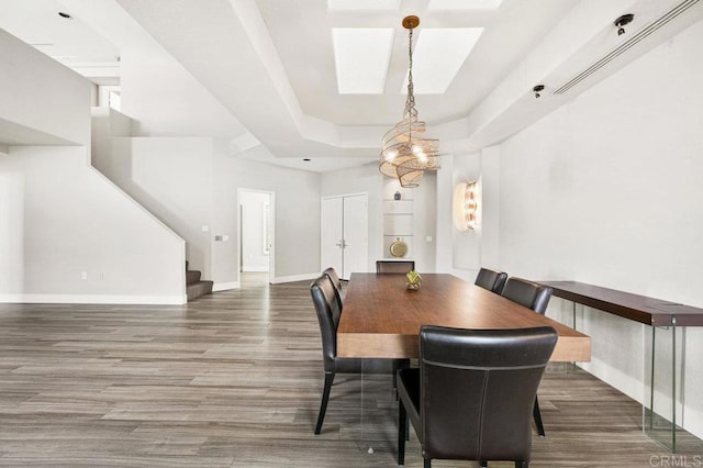 dining space with a raised ceiling and dark wood-type flooring