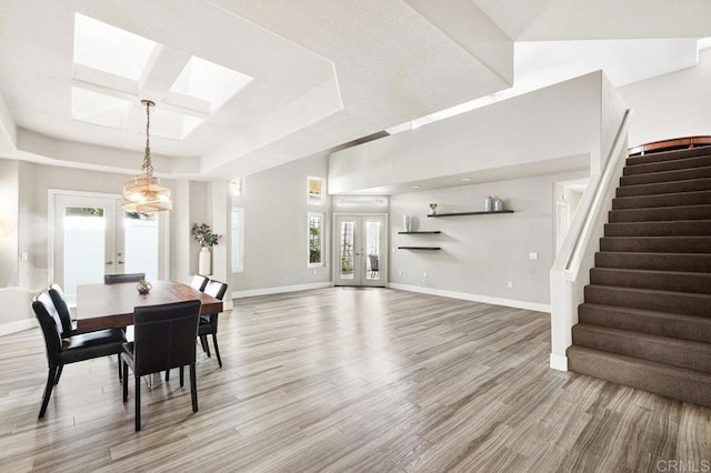 dining area with wood-type flooring, french doors, and a raised ceiling