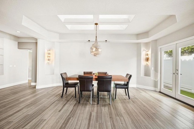 dining space featuring a tray ceiling, french doors, and hardwood / wood-style flooring