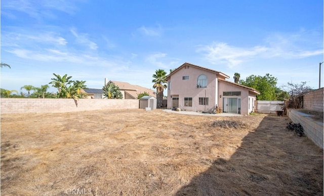 back of house with a storage shed