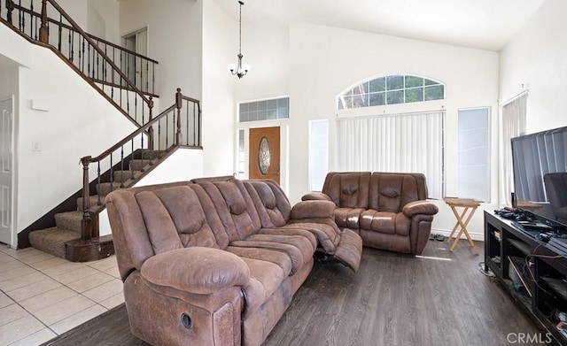 living room with a notable chandelier, hardwood / wood-style flooring, and a towering ceiling