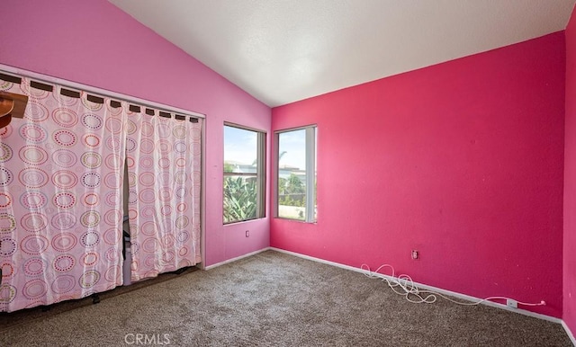 carpeted spare room with vaulted ceiling