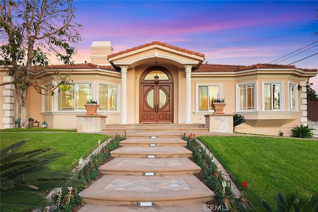 exterior entry at dusk featuring a yard