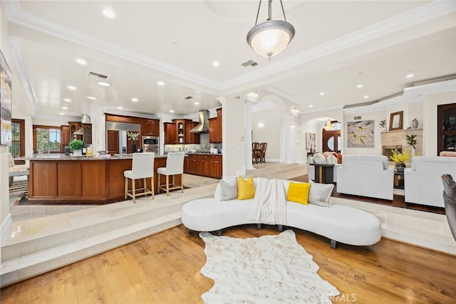 living room with crown molding, light hardwood / wood-style floors, and ornate columns