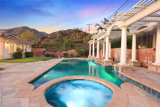 pool at dusk featuring an in ground hot tub, a pergola, a patio area, and a mountain view