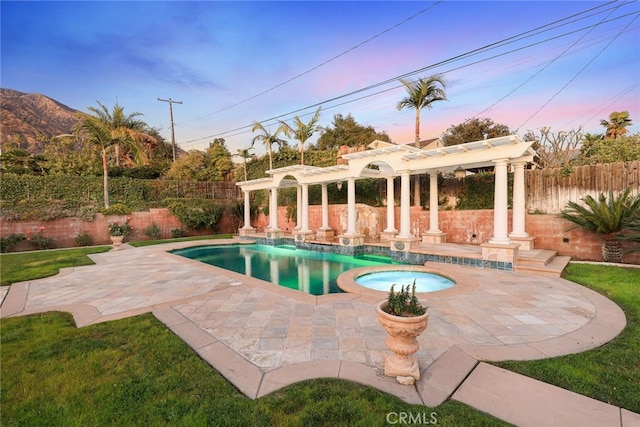 pool at dusk with an in ground hot tub, a pergola, and a patio