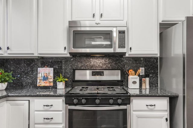 kitchen with stainless steel appliances, tasteful backsplash, dark stone countertops, and white cabinets