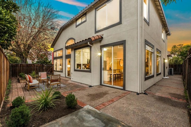 back house at dusk featuring an outdoor hangout area, central air condition unit, and a patio area