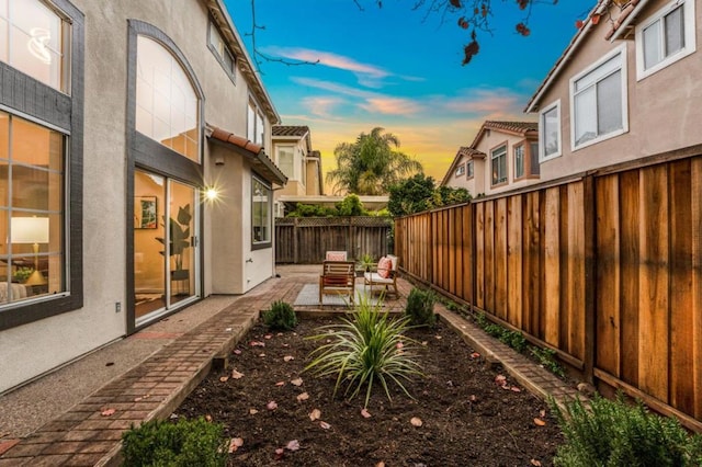 yard at dusk with an outdoor living space and a patio