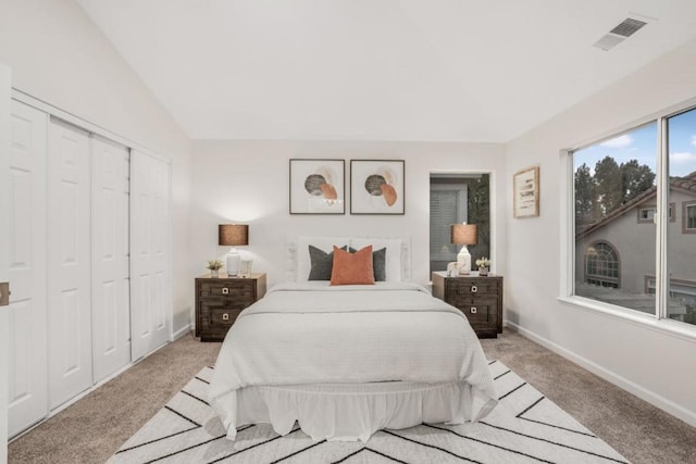 bedroom with vaulted ceiling, light colored carpet, and a closet