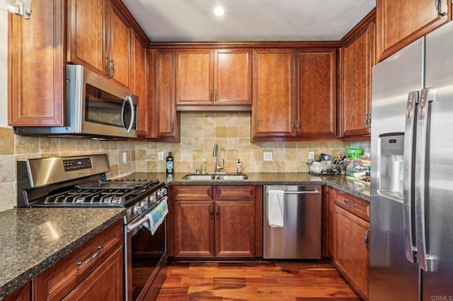 kitchen with appliances with stainless steel finishes, sink, and dark stone countertops