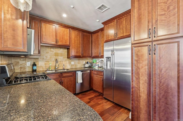 kitchen featuring dark hardwood / wood-style flooring, sink, dark stone counters, and appliances with stainless steel finishes