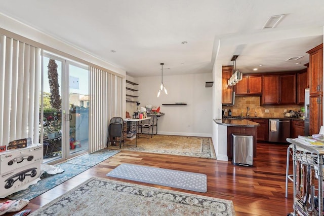 kitchen featuring dark wood-type flooring, sink, hanging light fixtures, dishwasher, and backsplash