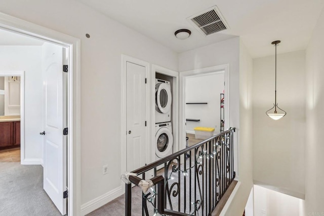 corridor featuring light carpet and stacked washer / drying machine