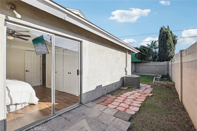 view of side of property with cooling unit, a fenced backyard, and stucco siding