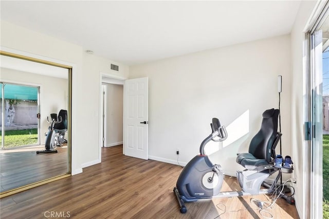 workout room featuring baseboards, visible vents, and wood finished floors