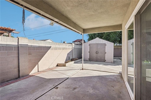 view of patio with an outbuilding, a storage unit, and a fenced backyard