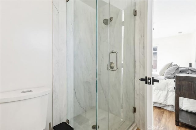 ensuite bathroom featuring toilet, wood finished floors, connected bathroom, and a marble finish shower