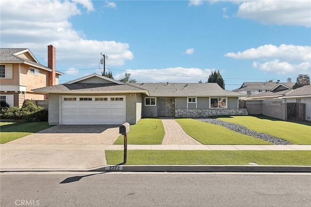 view of front facade featuring a garage, fence, driveway, stucco siding, and a front lawn