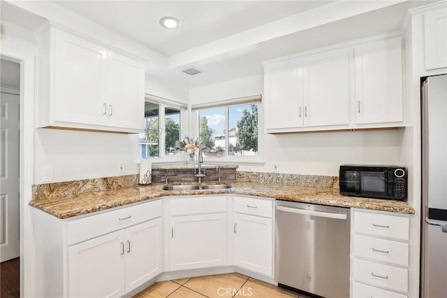 kitchen featuring light stone countertops, white cabinetry, appliances with stainless steel finishes, and a sink