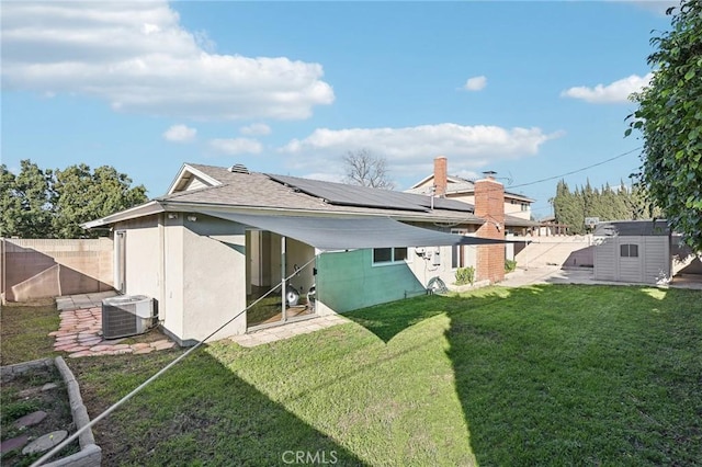 rear view of property featuring a fenced backyard, an outbuilding, a yard, a shed, and central AC