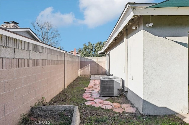 view of property exterior with stucco siding, a fenced backyard, and central air condition unit