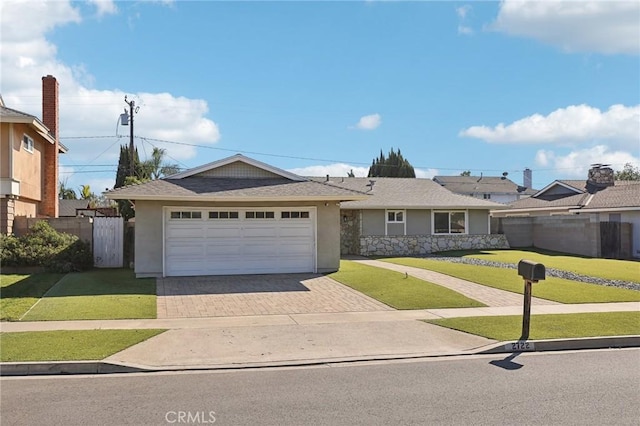 ranch-style home with an attached garage, fence, decorative driveway, stucco siding, and a front lawn