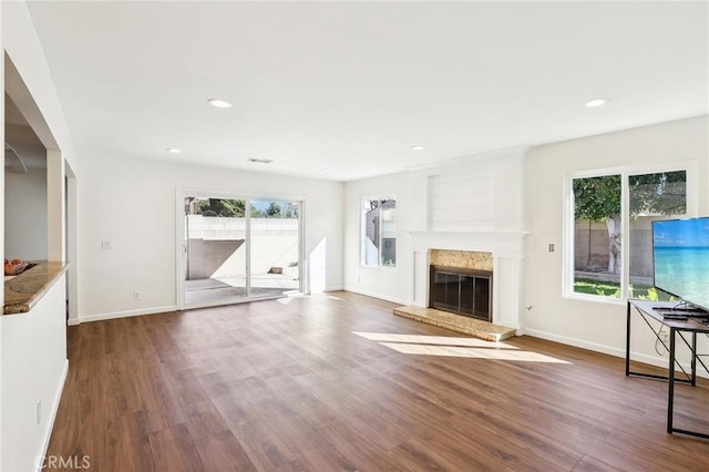 unfurnished living room with a glass covered fireplace, recessed lighting, baseboards, and wood finished floors