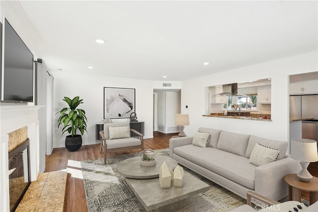 living room featuring recessed lighting, visible vents, light wood finished floors, and a tile fireplace