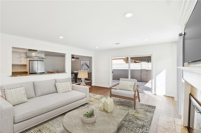 living room featuring a fireplace, recessed lighting, light wood-style floors, ceiling fan, and baseboards