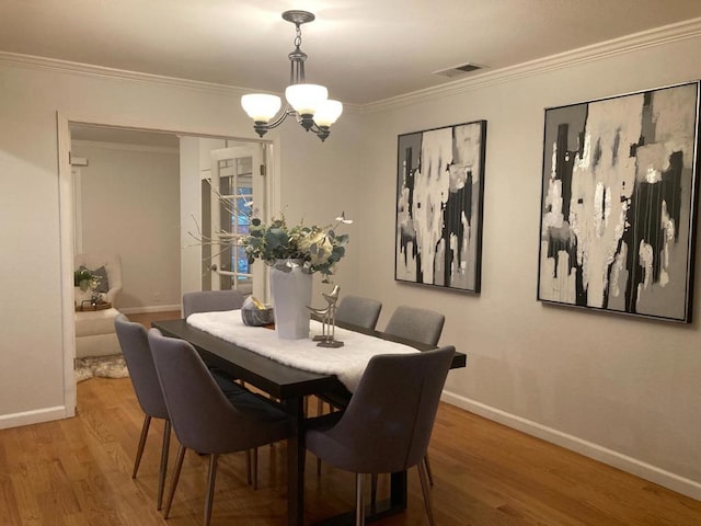 dining area featuring crown molding, a chandelier, and hardwood / wood-style flooring