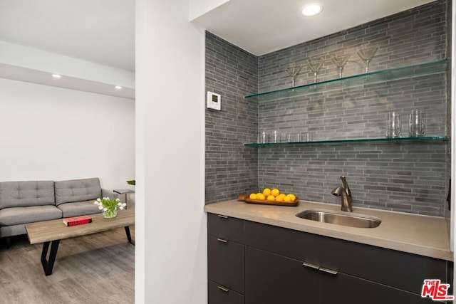 bar featuring tasteful backsplash, sink, and light hardwood / wood-style floors