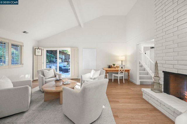 living room with beamed ceiling, a brick fireplace, high vaulted ceiling, and light hardwood / wood-style floors