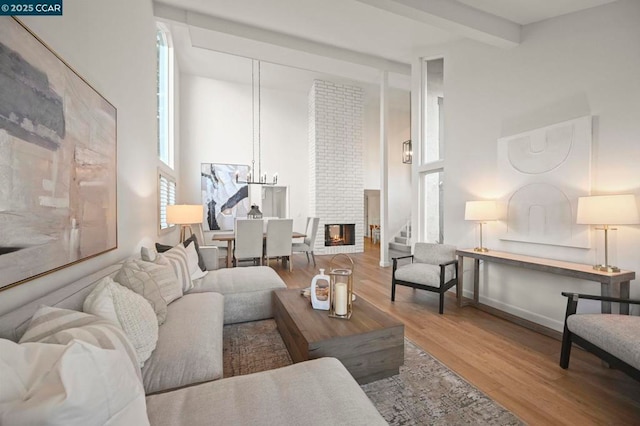 living room with hardwood / wood-style flooring, a fireplace, beamed ceiling, and a towering ceiling