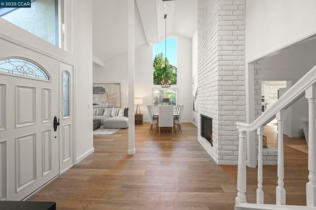 entrance foyer with hardwood / wood-style flooring, a fireplace, and high vaulted ceiling