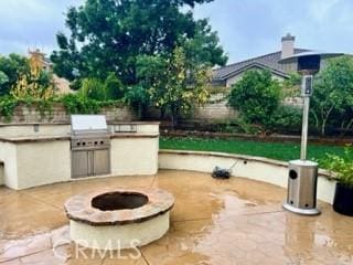 view of patio with a grill, exterior kitchen, and a fire pit